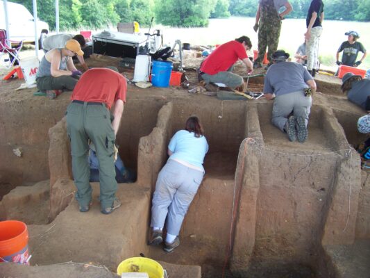 Excavators bent over units digging.